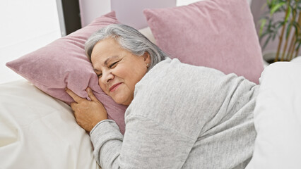 Smiling senior woman relaxing comfortably in a cozy bedroom setting