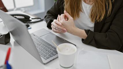 A businesswoman at her office desk, with laptop and coffee, poised and ready for work.