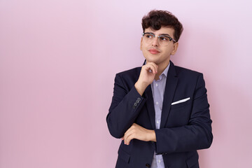 Young non binary man with beard wearing suit and tie with hand on chin thinking about question, pensive expression. smiling with thoughtful face. doubt concept.
