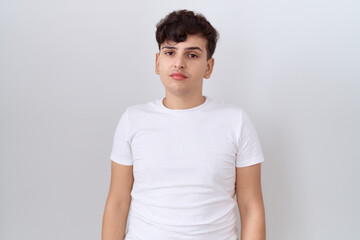 Young non binary man wearing casual white t shirt relaxed with serious expression on face. simple...