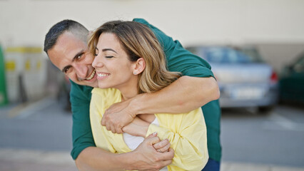 Fototapeta premium Man and woman couple hugging each other smiling at street