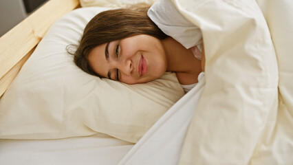 A young hispanic woman rests peacefully in a bedroom setting, exuding a sense of relaxation and comfort.