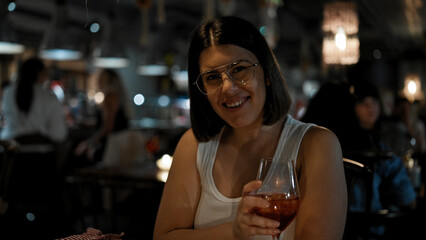 Young beautiful hispanic woman drinking a glass of red wine at the restaurant