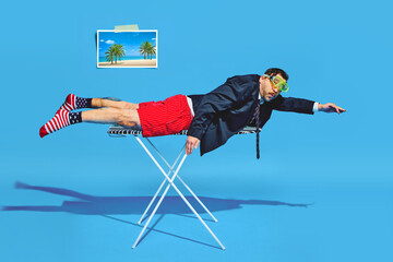 Young businessman lying on ironing board as on surfing board and rows with his arms as if he...