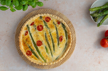 Homemade tart with green asparagus and cherry tomatoes on a stone background. Food photography. Quiche with green asparagus, eggs and parmesan cheese. Summer food