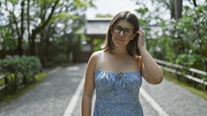 Beautiful young hispanic woman wearing glasses standing smiling at kyoto temple