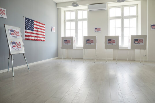 Empty polling station with row of white voting booths decorated with American flag at vote center. Presidential American elections in the United States. Democracy and election day concept.