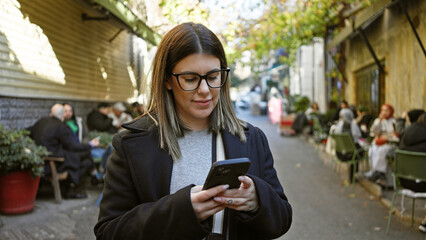 Young adult woman using smartphone on a historic street in istanbul, turkey.