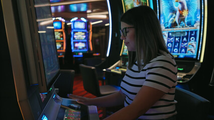 Young adult hispanic woman playing a slot machine at a casino, focused and eager to win.