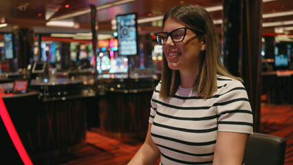 A smiling young adult hispanic woman enjoying herself at a lively casino environment, portraying...