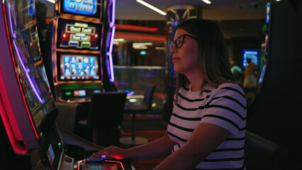 Adult woman gambles at a slot machine in a vibrant casino, displaying leisure, gaming, luck, and...