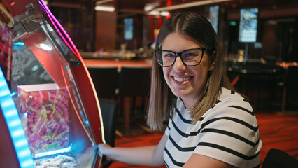 A cheerful young woman plays a slot machine in a vibrant casino, reflecting leisure and excitement.