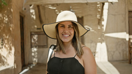 Smiling woman with hat at traditional market in dubai showcasing tourism and culture.
