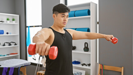 Young asian man exercises with dumbbells in a rehabilitation center