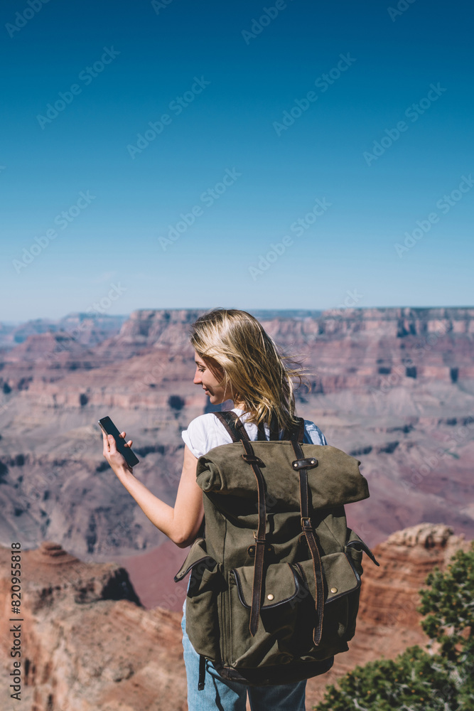 Aufkleber young hipster girl reading message on smartphone standing on mountains viewpoint using roaming, fema