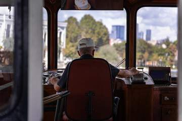 Adult male ferry captain in the wheelhouse is sailing along the route, rear view. © yaroslav1986