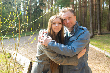 portrait of a happy father and his teenage daughter in a spring park.	