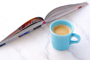 テーブルの上の開いた本とコーヒーカップで、コーヒーを飲みながら読書を楽しむイメージ
