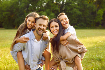 Happy family having a good time together in nature. Portrait of a cheerful father and mother piggy...