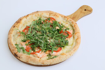 Pizza with shrimp, salmon and arugula on a wooden board on white background