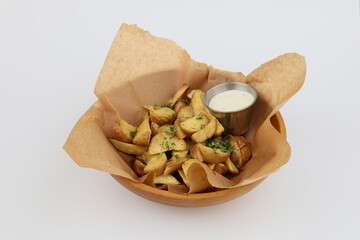 Baked potatoes with aioli sauce in a wooden plate on a white background
