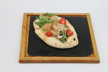 Half a chicken in pita with greens and tomatoes on a board on a white background