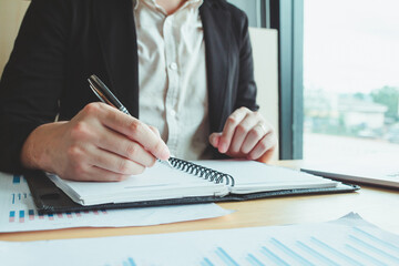 A student intensely studying and writing in a notebook, preparing for an upcoming exam in a university classroom setting, highlighting the importance of education and academic success