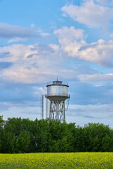 water tower in the field against the blue sky and clouds
