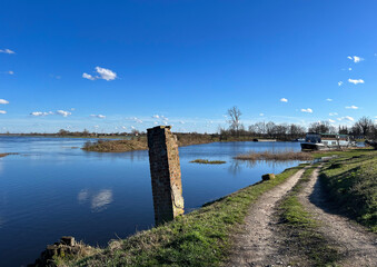 Beautiful spring landscape.
River flood. Blue sky. Reflections in the water.