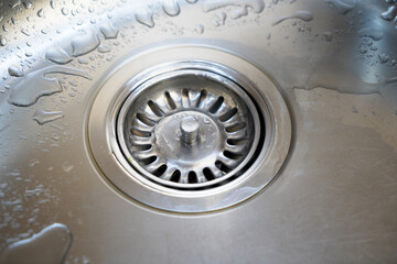 Stainless steel sink and water drain in a modern kitchen, water flow in the kitchen sink