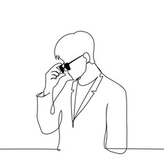 man in a suit puts on or takes off sunglasses - one line art vector. businessman concept in glasses