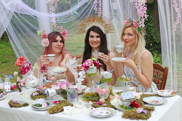 Drei als Elfen oder Feen verkleidete Frauen sitzen fröhlich an einem Teetisch