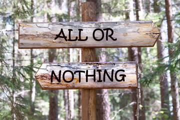 All or nothing, motivational phrase, inscription on the wooden signpost against the background of the forest