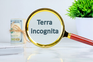 Terra incognita the phrase means unknown land written through a magnifying glass on a gray background