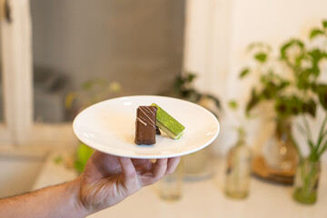 pieces of handmade chocolate decorated on a plate held with one hand