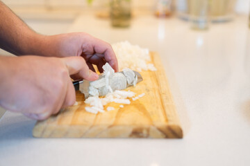 man cutting onion on a wooden board in horizontal view