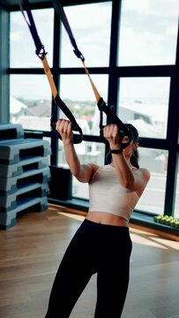 Beautiful woman doing exercise with trx system.Fitness exercises with loops.Concept workout healthy lifestyle sport.Vertical video