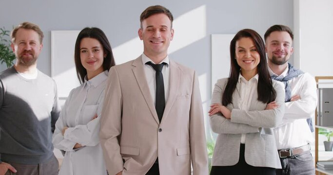 Team headed by leader who radiates charisma and confidence next to same professional colleagues. Smiling business women and men in front of camera come forward one by one to their leader. 4k footage.
