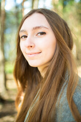 Portrait of a beautiful young girl with long hair in the forest