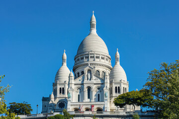 Fototapeta na wymiar The white domes of Sacre-Coeur Basilica stand out against a clear blue sky on Montmartre