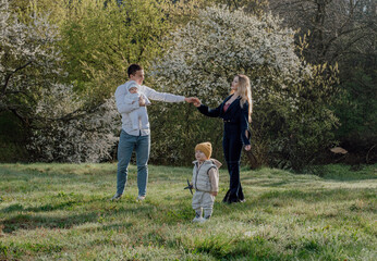 Fototapeta premium happy and cheerful young family with two kids enjoying spring sun outdoors. Young parents with kids playing outdoors