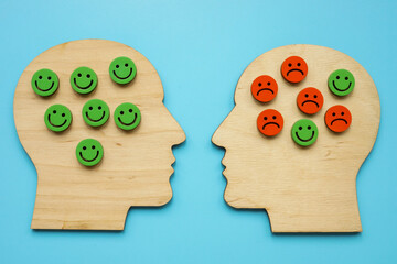 Wooden outlines of heads, happy and sad smiles. Stress, negative emotions and psychotherapy concept.