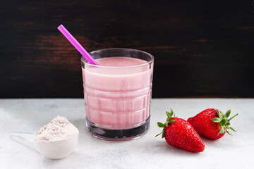 Strawberry smoothie, protein drink in a glass, measuring scoop with whey protein powder, blended...