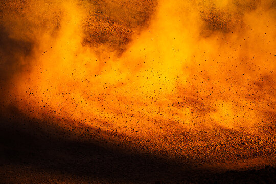 Dirt flies in the air along a track as a race car zooms past