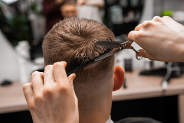 Using a combination of scissors and comb, the barber artfully crafts the mans hair at the barbershop