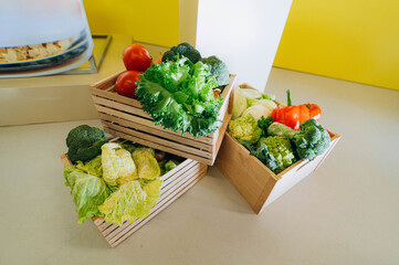 Wooden box with vegetables: cabbage, pepper, broccoli, onion, tomato, green salad
