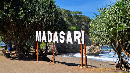 Madasari Sign with View of Madasari Beach with Coral Island with Cloudy Blue Sky Background in the...