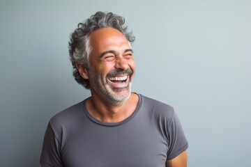 Fototapeta premium Portrait of a cheerful man in his 50s laughing in front of minimalist or empty room background