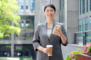Confident Businesswoman with Smartphone and Coffee Outside
