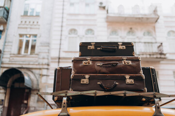Relocation. A pile of vintage bags on the roof of a car. old suitcases with things on the roof of a yellow taxi.
